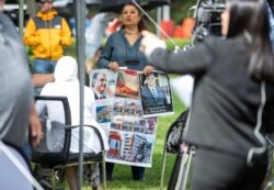 A woman holds images, some showing former Lebanon Prime Minister Rafik Hariri, outside the United Nations-backed Lebanon Tribunal in Leidschendam, Netherlands, Aug. 18, 2020.