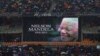 Spectators shelter under umbrellas as the rain lashes down during the memorial service for former South African president Nelson Mandela at the FNB Stadium in Soweto, near Johannesburg, South Africa, Dec. 10, 2013.
