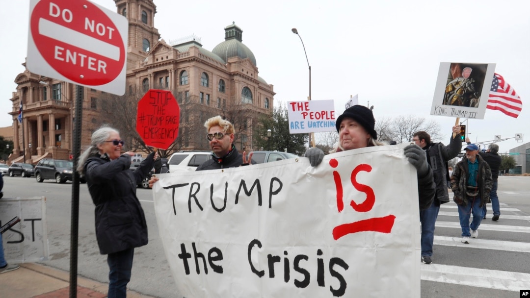 Carolyn Hursh, right, and Joey Daniel, carry a sign during a protest with others in downtown Fort Worth, Texas, Feb. 18, 2019. People gathered on the Presidents Day holiday to protest President Donald Trump's recent national emergency declaration.