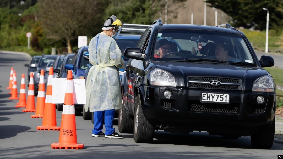 Medical staff prepare take a COVID-19 test from a visitor to a drive through community based assessment center in Christchurch, New Zealand, Aug. 13, 2020.