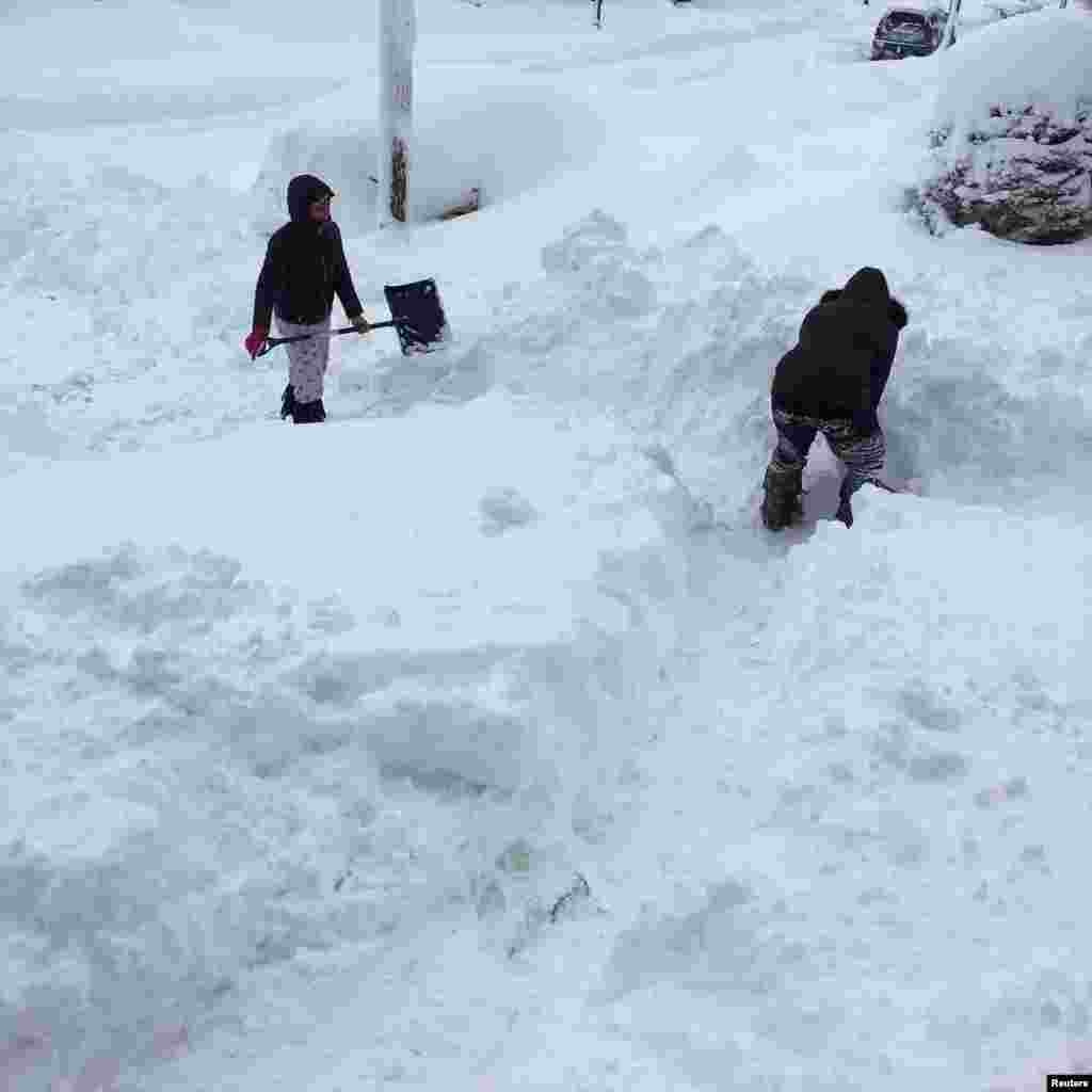 People dig out the path by their house after the record snowfall in Erie, U.S. in this picture obtained from social media. Courtesy of Instagram @DANIELLESOFANCY /via REUTERS