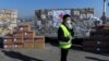 希腊雅典国际机场的一名工人站在从中国运抵的口罩等抗疫防护用品。（2020年3月21日）