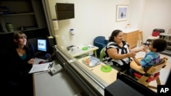 Clinical specialist Catey Funaiock, left, observes from behind a one-way mirror as Marlaina Dreher, left, plays with her 5-year-old son Brandon after he fed himself during a session in the pediatric feeding disorder program at the Marcus Autism Center, Sept. 18, 2013, in Atlanta, Georgia. 