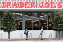 People practice social distancing as they wait in line to enter a grocery store, April 7, 2020, in Miami Beach, Florida.