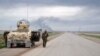 Smoke billows in the background as Kurdish Peshmerga fighters take positions on the side of a road in the northern Iraqi city of Kirkuk, Jan. 30, 2015.