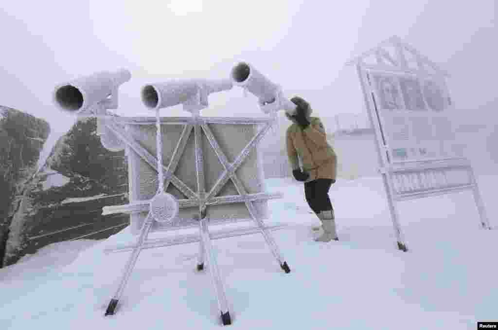 A woman looks through a telescope, covered with hoarfrost, with the air temperature at about minus 38° C (- 36.4° F) on the bank of the Yenisei River in the Siberian village of Ovsyanka near Krasnoyarsk, Russia, Jan. 20, 2018.