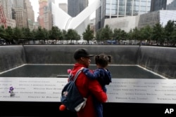 Un hombre y su hija observan la fuente norte en el World Trade Center en Nueva York durante la ceremonia recordatorai de los ataques terroristas de 2001 el martes, 11 de septiembre de 2018.