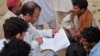 Naim ullah Khattak (L), an Election Commission of Pakistan (ECP) worker, verifies voters using a list from the Computerized National Identity Card (CNIC) database in the outskirts of Islamabad on Sept. 12, 2011.