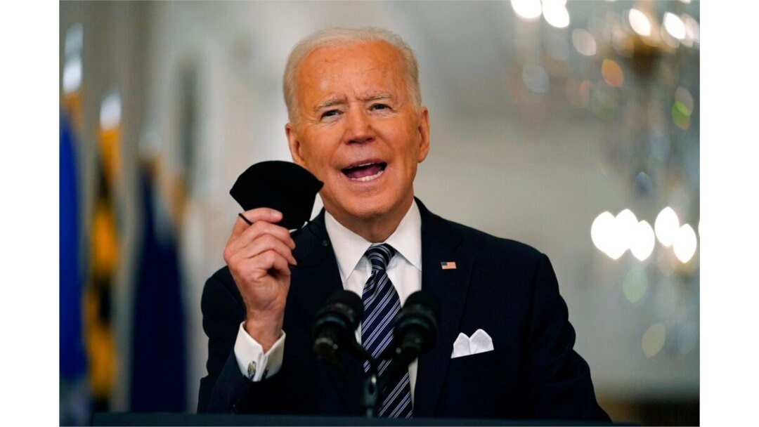 President Joe Biden holds up his face mask as he speaks about the COVID-19 pandemic during a prime-time address from the East Room of the White House, March 11, 2021.