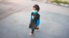 FILE - An Afghan girl wears a protective mask as she walks out of a school in Herat province, Nov. 3, 2009.