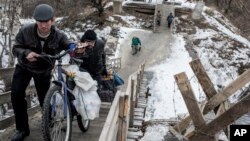 Мешканці Станиці Луганської перетинають міст, ушкоджений у ході бойових дій.