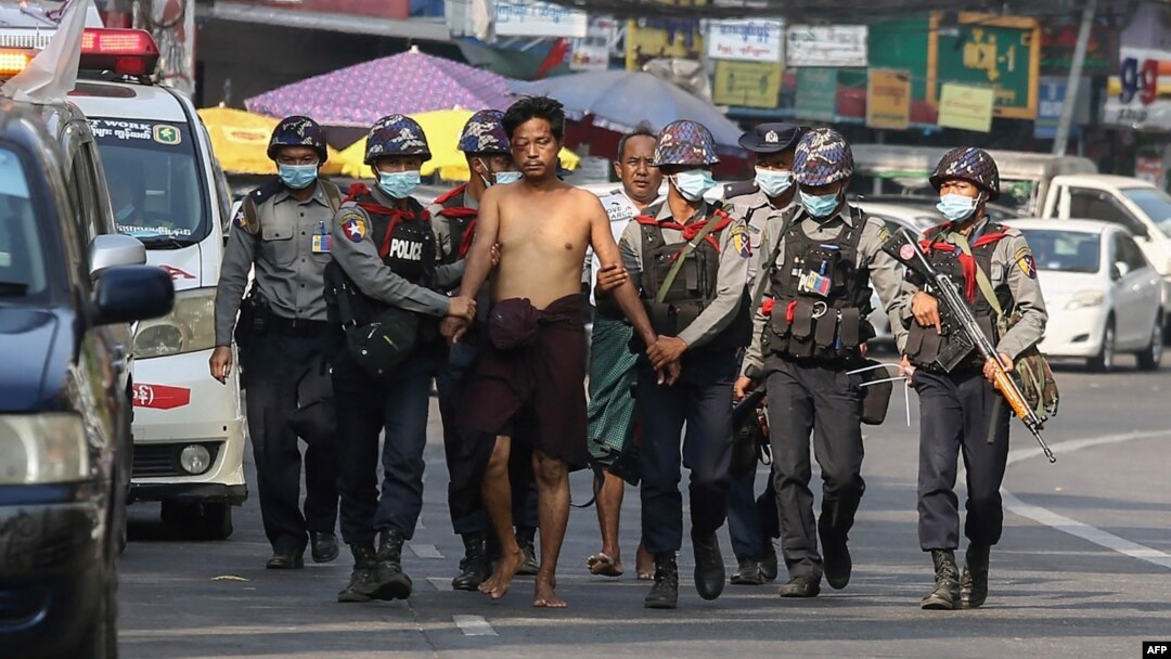 In this file photo taken on February 26, 2021, police march with a resident arrested during a crackdown on protesters holding rallies against the military coup in Yangon. (Photo by AFP)
