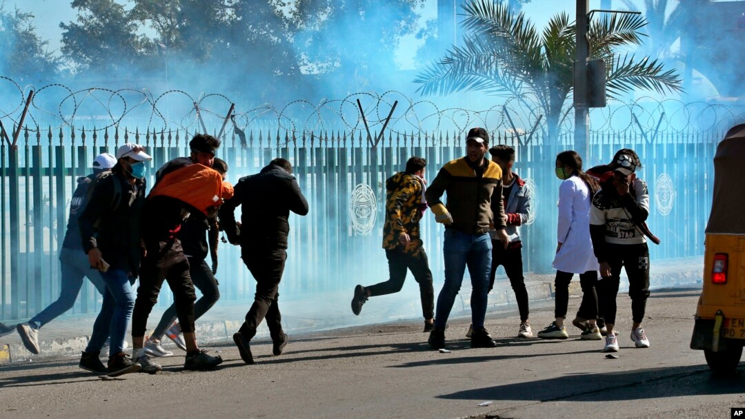 Anti-government protesters run as security forces fire tear gas to disperse them during a clash in Baghdad, Iraq, Jan. 26, 2020. 