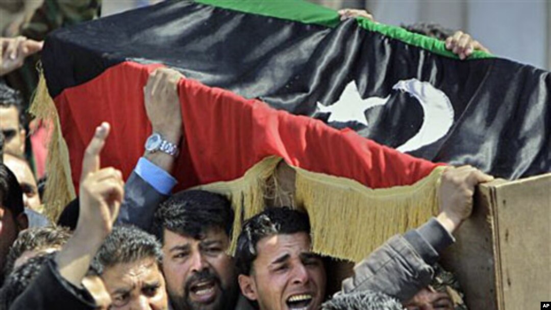 Mourners carry a coffin draped in the opposition flag at a funeral for some of those killed by Thursday's airstrike on rebel forces in Benghazi,Apr 8 2011