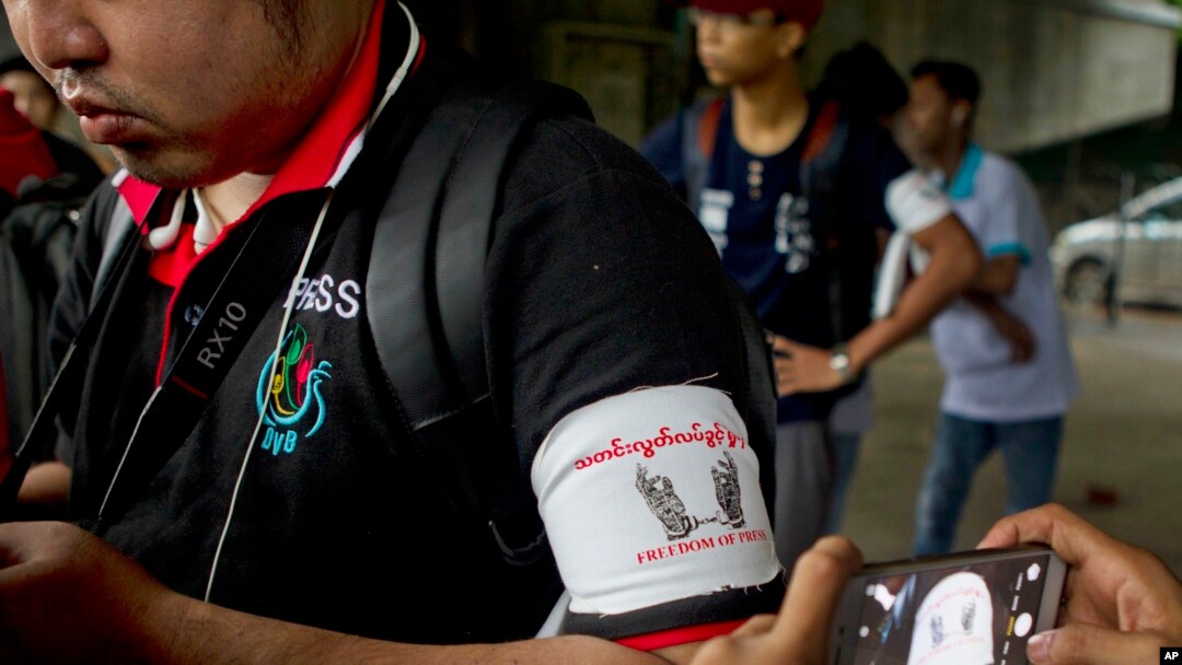 FILE - A local journalist wears an arm band supporting press freedom as he gathers with other journalists during the court appearance of a newspaper editor and a columnist at a township court.