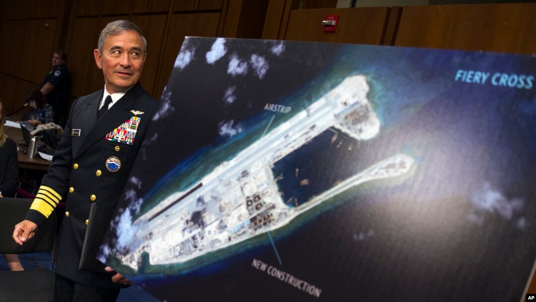 FILE - Adm. Harry B. Harris, Jr., US Navy Commander, U.S. Pacific Command walks past a photograph showing an island that China is building on the Fiery Cross Reef in the South China Sea, as the prepares to testify on Capitol Hill in Washington, Sept. 17, 2015, 