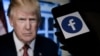 FILE - A phone screen displays a Facebook logo with the official portrait of former U.S. President Donald Trump in the background in Arlington, Va., May 4, 2021.