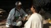 FILE - A Pakistani street barber prepares to cut a customer's hair, along a roadside in Lahore.