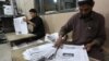 FILE - Afghan workers arrange copies of the 8AM daily newspaper in Kabul, Afghanistan.