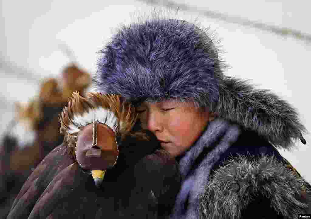 A young hunter rests next to his tamed golden eagle during an annual hunters competition at Almaty hippodrome, Kazakhstan February 9, 2018. 