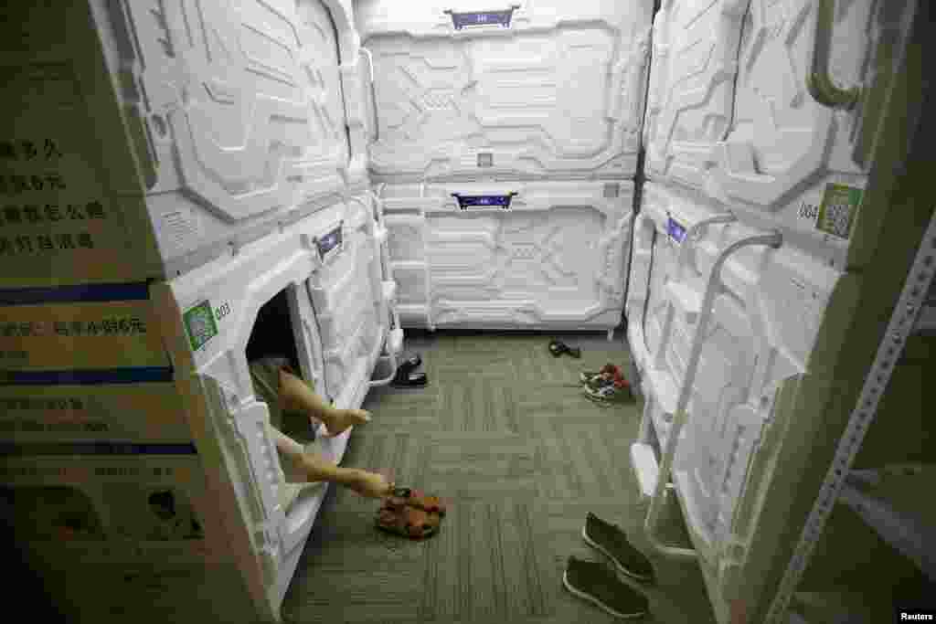 An IT employee takes off his shoes as he prepares to sleep in a capsule bed unit at Xiangshui Space during a lunch break, in Beijing's Zhongguancun area, China.