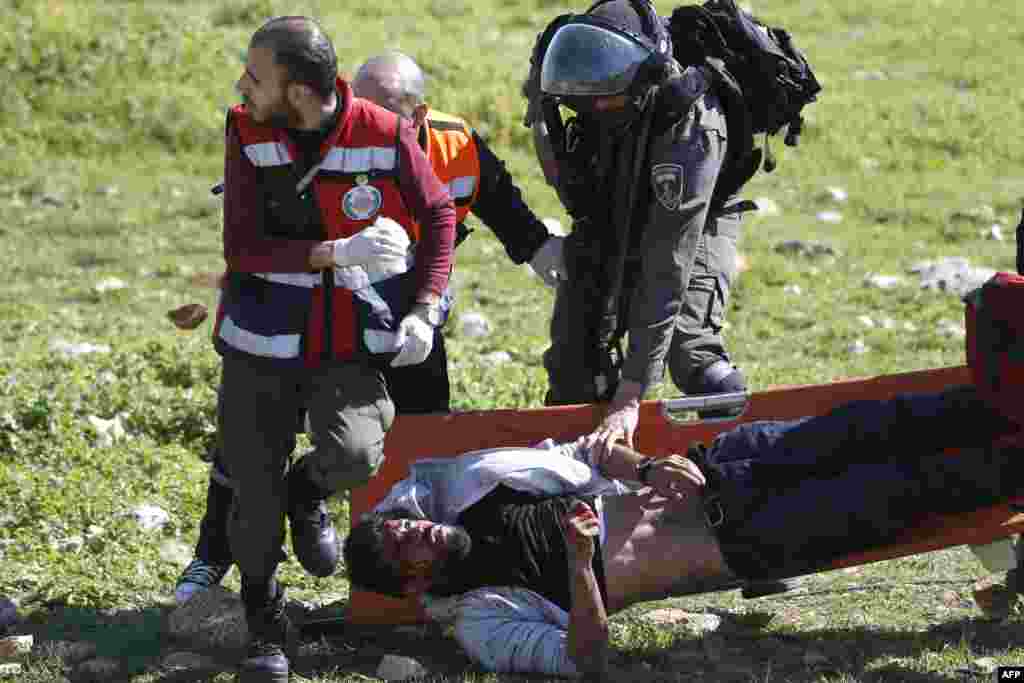 An Israeli soldier attempts to detain an injured Palestinian demontrator as he's carried on a stretcher by Palestinian Civil Defense volunteers in the West Bank town of Birzeit, near Ramallah, during a protest by students of the Birzeit University against the arrest of the the head of Palestinian student council by an Israeli undercover commando.