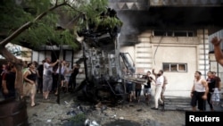 Palestinians inspect a car after it was blown up in Gaza City July 19, 2015. 