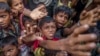FILE - Rohingya Muslim children, who crossed over from Myanmar into Bangladesh, stretch out their arms out to collect chocolates and milk distributed by Bangladeshi men at Taiy Khali refugee camp, Bangladesh, Sept. 21, 2017. 
