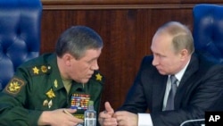 FILE - Russian President Vladimir Putin, right, speaks with Chief of the General Staff of the Russian Armed Forces Valery Gerasimov at a meeting with top military officials in the National Defense Control Center in Moscow, Russia.