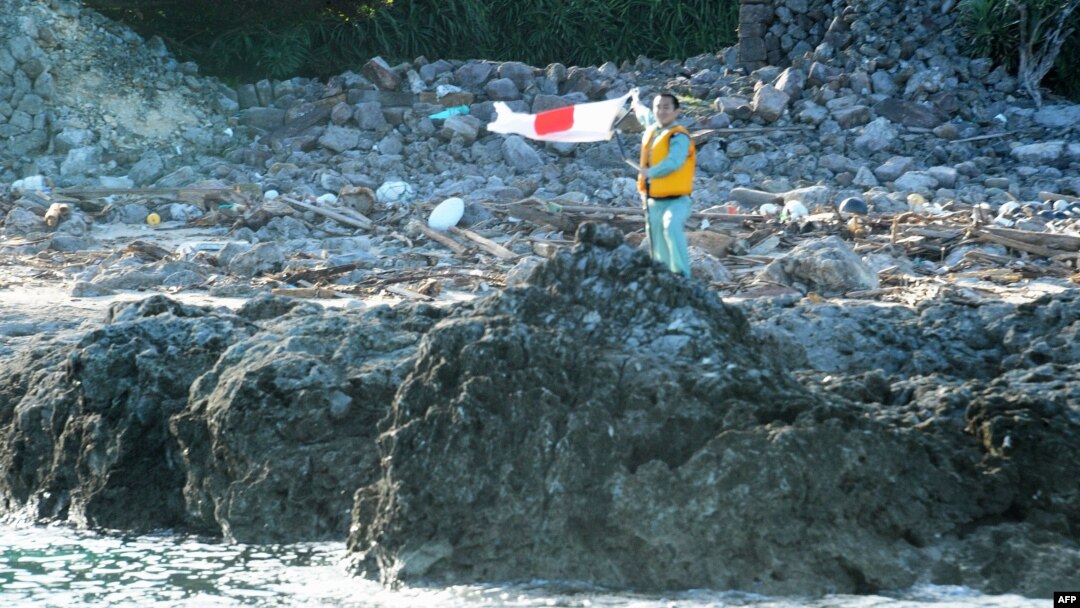 A Japanese activist waves the country's flag after landing on a group of islands known as Senkaku in Japanese and Diaoyu in Chinese, August 19, 2012.