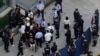 Investors are surrounded by police and security personnel as they try to enter the headquarters of the real estate developer Evergrande Group, Sept. 23, 2021, in Shenzhen, China. 