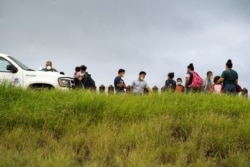 FILE - Asylum-seeking migrants from Central America are processed by the U.S. Border Patrol agents after crossing the Rio Grande into the United States from Mexico, in Penitas, Texas, July 8, 2021.
