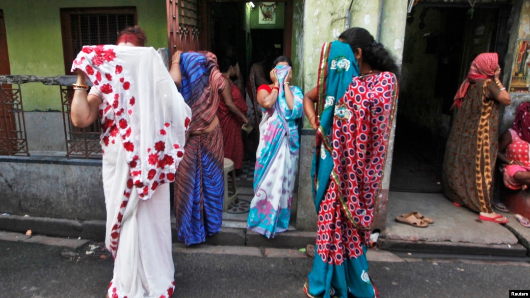 Indian sex workers cover their faces at the Sonagachi red-light area in Kolkata July 24, 2012.