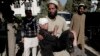FILE - An Afghan man carries an injured boy to a hospital after two roadside bombs struck the Achin district of Jalalabad, east of Kabul, Afghanistan, Nov. 28, 2013.
