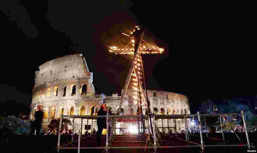 A worker lights a cross before Pope Francis leads a Via Crucis (Way of the Cross) procession during Good Friday celebrations in front of the Colosseum in Rome, March 29, 2013.
