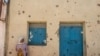 FILE - A woman leans on the wall of a damaged house which was shelled as federal-aligned forces entered the city, in Wukro, north of Mekele, in Tigray, March 1, 2021. 