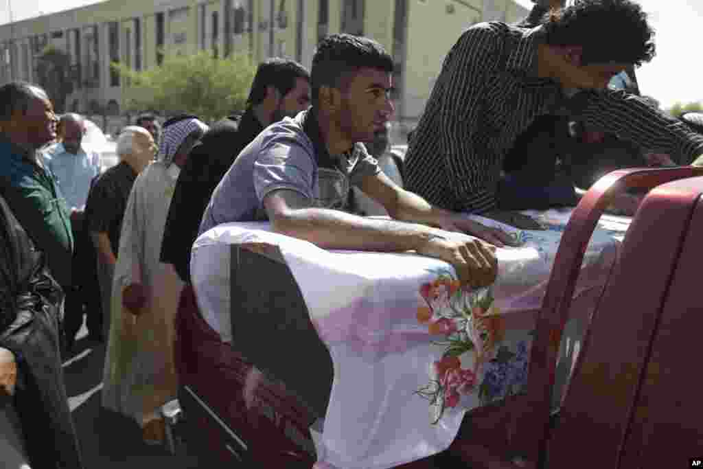 Relatives of a man who was killed in a car bomb attack grieve over his casket during his funeral in Baghdad, August 15, 2013.