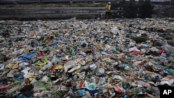 FILE - A man walks on the shores the Arabian Sea, littered with plastic and other garbage in Mumbai, India, June 4, 2018. The theme for that year's World Environment Day, marked on June 5, is "Beat Plastic Pollution." 