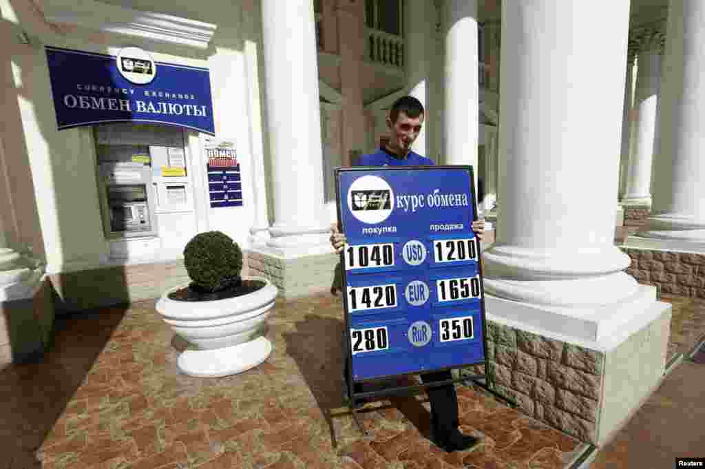 A man carries a placard with currency rates at an exchange office in Sevastopol, Crimea, March 24, 2014.