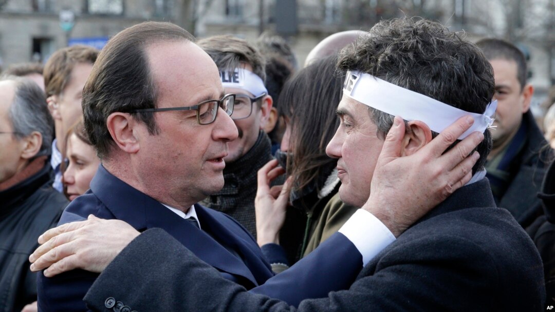 French President Francois Hollande comforts French columnist for Charlie Hebdo Patrick Pelloux in a solidarity march in the streets of Paris, Jan. 11, 2015.