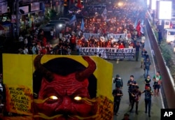 FILE - Protesters carry torches as they march toward the Presidential Palace in Manila to mark the U.N. Declaration of International Human Rights Day, Dec. 10, 2017, in Manila, Philippines.