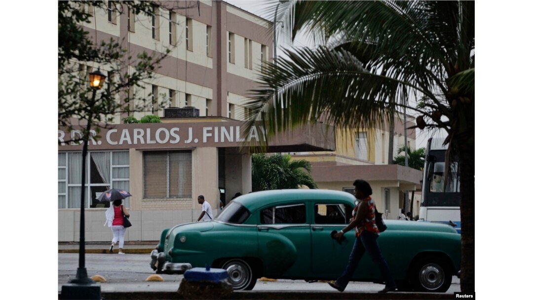 FILE - People walk beside the Carlos J. Finlay Military Hospital where U.S. government contract worker Alan Gross is held prisoner in Havana, March 19, 2013.