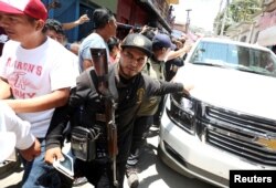 FILE - Members of the Community Police help open a road as leftist front-runner Andres Manuel Lopez Obrador of the National Regeneration Movement (MORENA) leaves a campaign rally in Tlapa de Comonfort, in Guerrero state, Mexico, June 7, 2018.