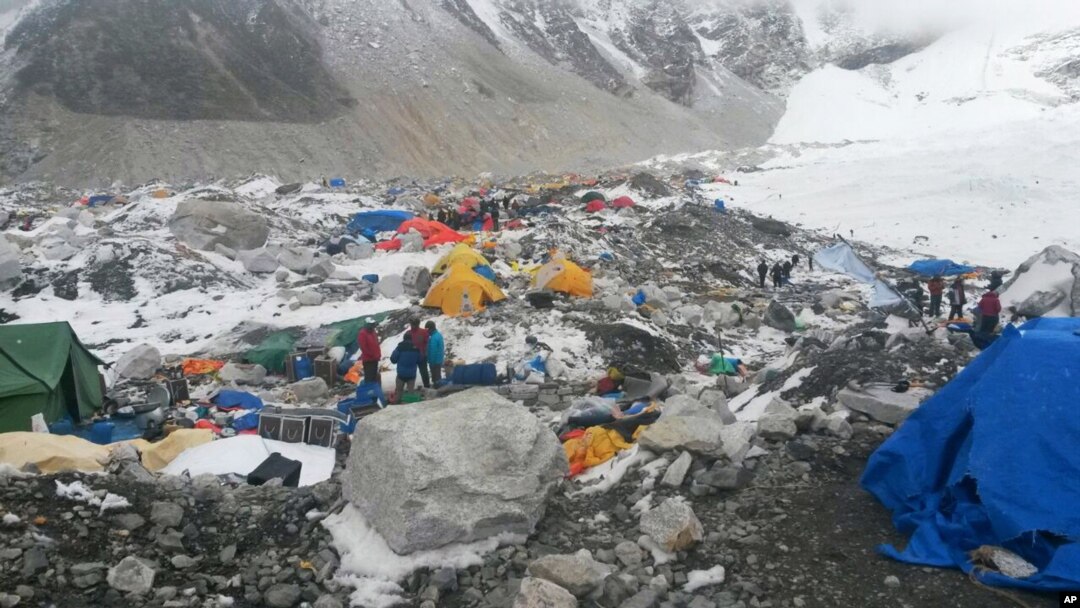 FILE – In this April 28, 2015 file photo, guides and climbers stand beside gear piled up after an avalanche triggered by the massive 7.8 magnitude earthquake hit the area.