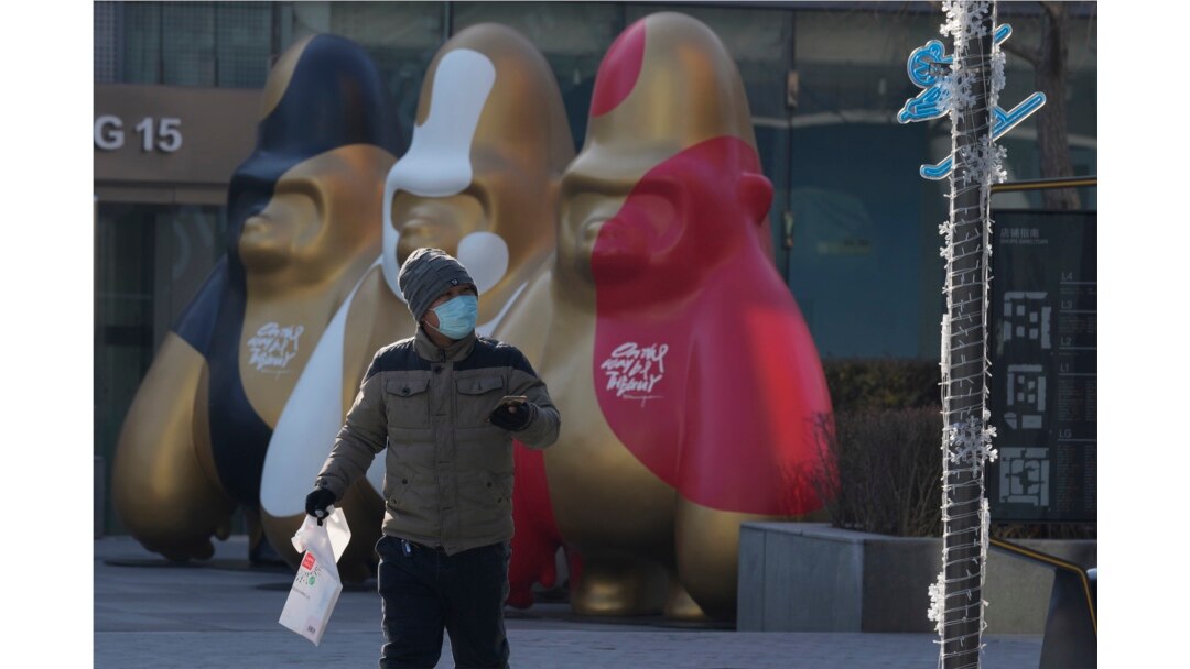 A man wearing a mask walks near decorations at a shopping mall in Beijing, Dec. 14, 2021. Chinese state media said Monday, Dec. 13, 2021, that the first case of the omicron variant of COVID-19 has been detected in the country's mainland in Tianjin city ju