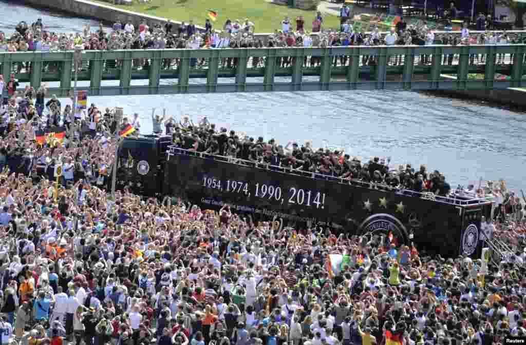Fans throng a street along the river Spree in central Berlin to cheer Germany's 2014 Brazil World Cup squad as they proceed in an open-top bus through the capital during a parade to mark the team's victory.
