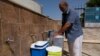 FILE - A man fills jerrycans with water in Derna, Libya, June 13, 2018. Sunday, an armed group stormed Tripoli's main water distribution station, imperiling water supplies for up to two million people.