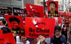FILE - Demonstrators hold signs protesting an extradition bill during a rally in Hong Kong, June 9, 2019.