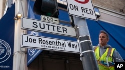An worker installs the Joe Rosenthal Way street sign to honor Rosenthal, who won the Pulitzer Prize for his iconic photo of US Marines raising the flag on the Japanese island of Iwo Jima during WWII, Dec. 12, 2024, in San Francisco. 