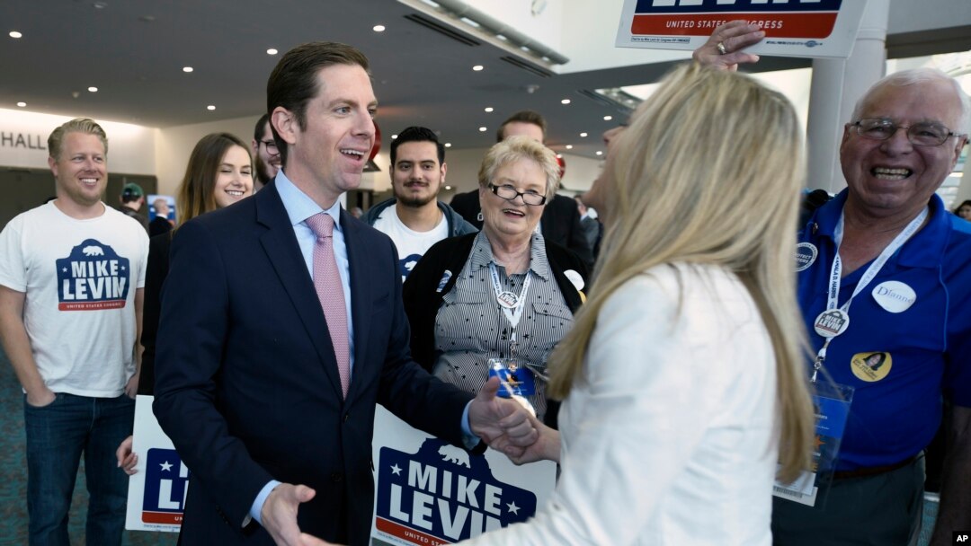 Democratic congressional candidate Mike Levin talks with his wife, Chrissy Levin, in front of supporters at the 2018 California Democrats State Convention, Feb. 24, 2018, in San Diego. "Many voters are looking for someone who will be a check [on the administration] and not just a rubber stamp," he said. Levin is seeking the open seat in California's 49th District. 
